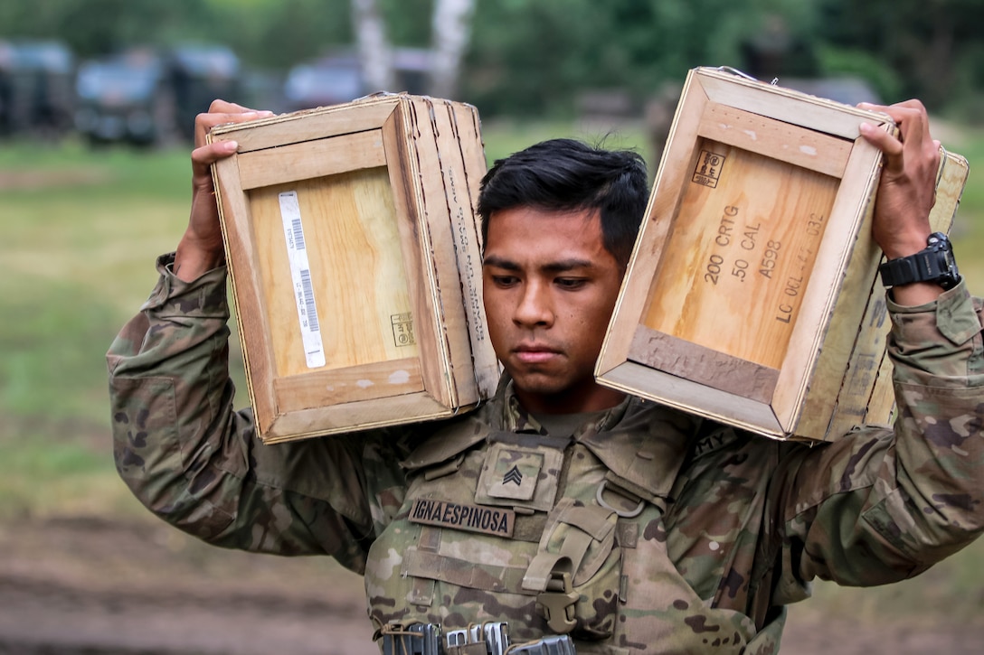 A soldier carries boxes of ammunition to prepare for training.