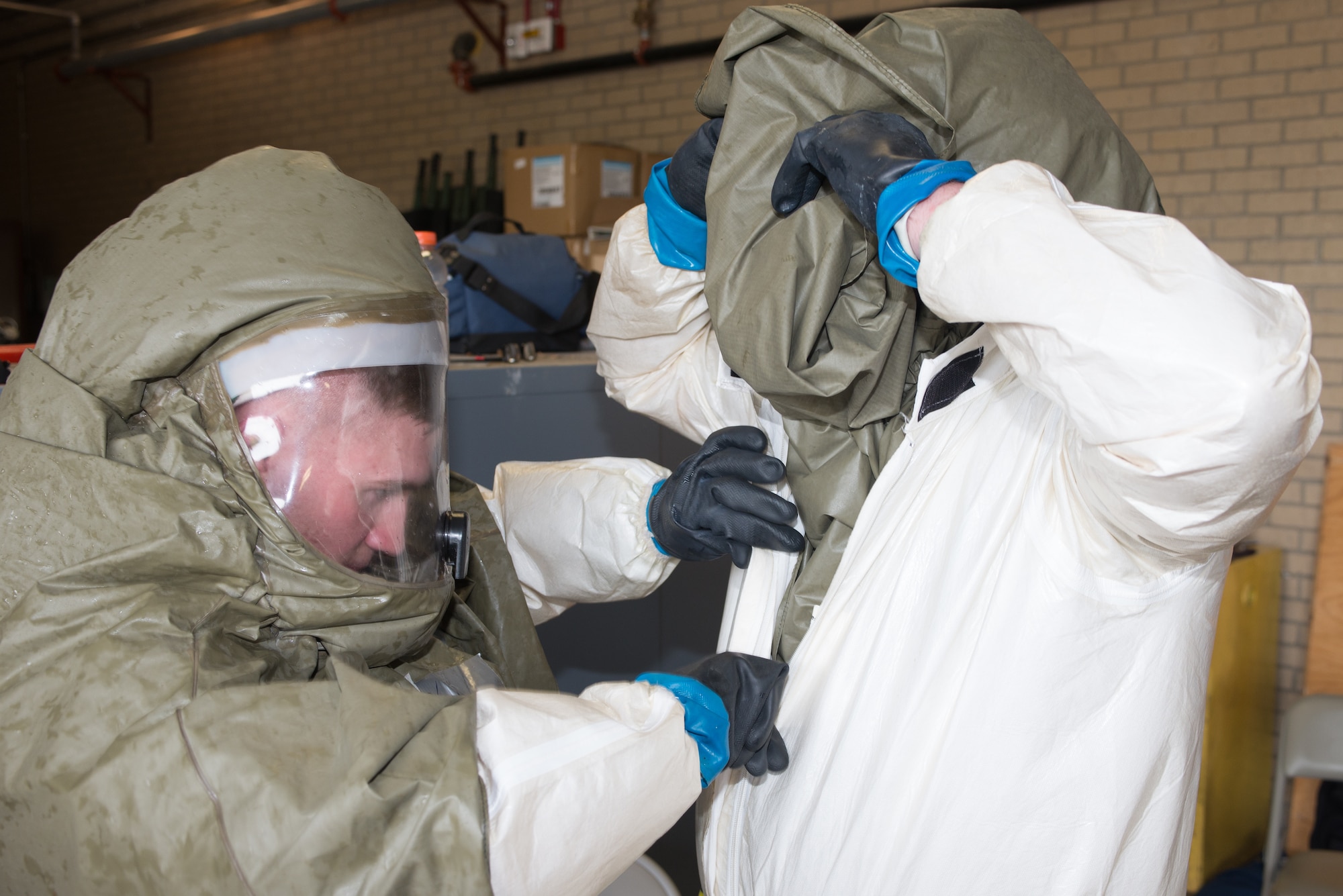 U.S. Air Force Senior Airman William Davis, 55th Medical Support Squadron pharmacy technician and member of the In-Place Patient Decontamination (IPPD) Team, checks the disposable toxic agent protective suit on a teammate during a product evaluation at the Ehrling Bergquist Clinic June 7, 2018, at Offutt Air Force Base, Nebraska. Members of the IPPD Team simulated working in a contaminated environment while testing three new patient decontamination systems. (U.S. Air Force photo by Paul Shirk)