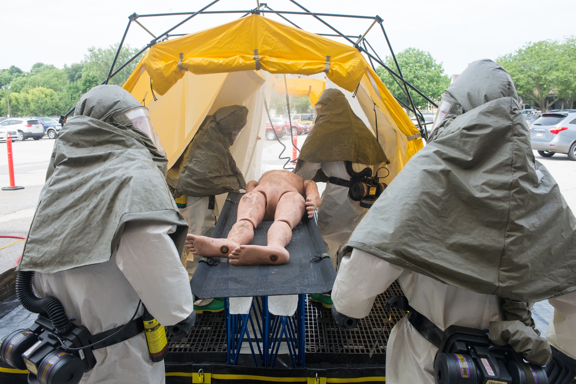 Members of the In-Place Patient Decontamination Team carry a mannequin into a patient decontamination system during a product evaluation at the Ehrling Bergquist Clinic June 7, 2018, at Offutt Air Force Base, Nebraska. The system is used to wash dangerous materials off of patients before they enter a military treatment facility. (U.S. Air Force photo by Paul Shirk)