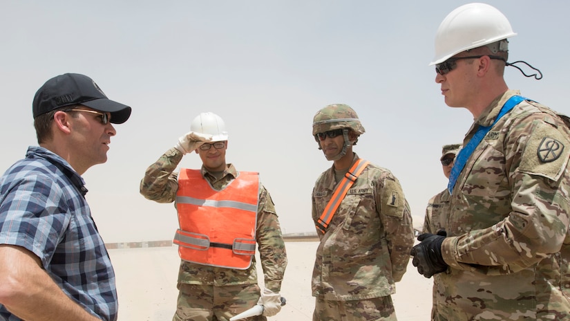 Secretary of the Army, Dr. Mark T. Esper asks Soldiers with the 401st Army Field Support Battalion about the different kinds of protective equipment they must wear while working outside of an Army Prepositioned Stock warehouse at Camp Arifjan, Kuwait, June 21, 2018. Soldiers wear safety equipment when they are moving vehicles out of the warehouse and on to a test track where they are driven as part of their maintenance inspections.