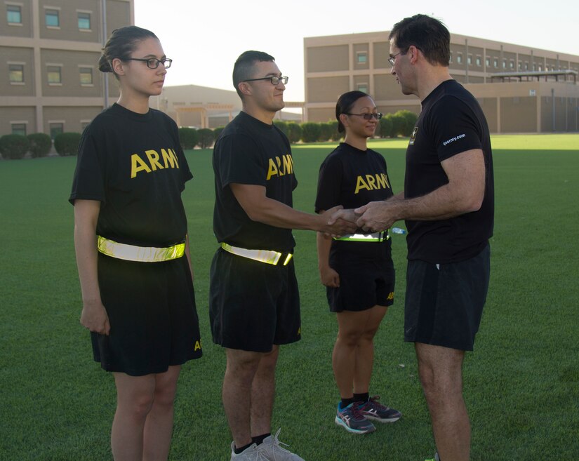 Secretary of the Army, Dr. Mark T. Esper, presents U.S. Army Spc. Matthew Trujillo, a customs specialist, assigned to the 236th Military Police Company, with the Secretary of the Army coin for his hard work and dedication, during physical readiness training with Soldiers from the 49th Theater Gateway Company at Camp Arifjan, Kuwait, June 21, 2018. Esper was honored to see junior Soldiers performing at a high level of professionalism.