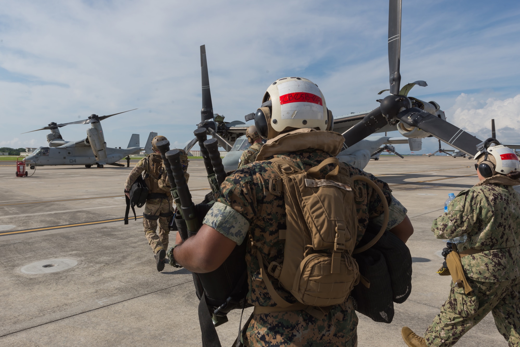 Members of the U.S. Air Force, Navy and Marines, board an MV-22 Osprey, June 6, 2018, at Marine Corps Air Station, Okinawa, Japan during an exercise. The Air Force performs joint medical exercises with other U.S. forces regularly in Okinawa to better prepare service members for real world emergencies. (U.S. Air Force photo illustration by Josh Mahler)