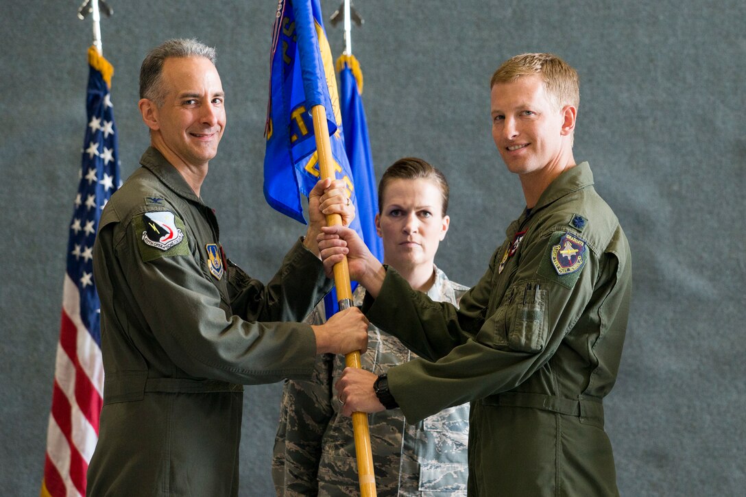 Col. Christopher Spinelli, 412th Operations Group Commander passes the 419th Flight Test Squadron guidon to Lt. Col. Thomas Meagher during a change of command ceremony June 15.