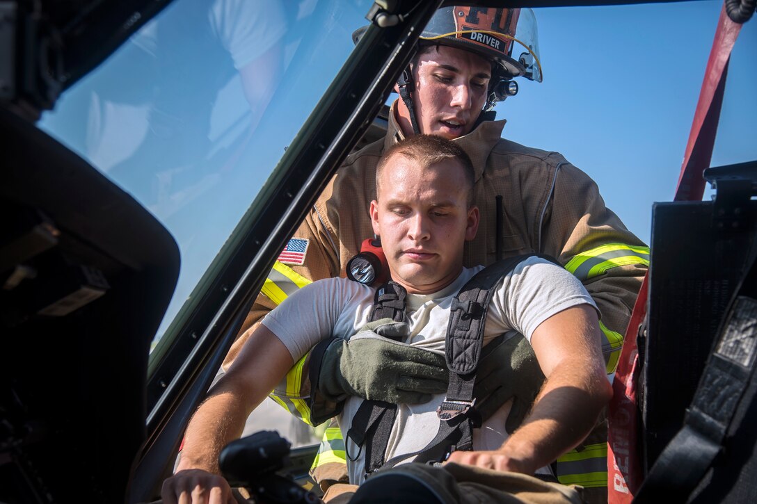 Senior Airman Justin Lang, rear, 23d Civil Engineer Squadron (CES) firefighter, recovers a simulated victim from an HH-60G Pave Hawk during a rescue training scenario, June 19, 2018, at Moody Air Force Base, Ga. 23d CES firefighters conducted the training to evaluate their overall knowledge and preparation of how to properly shut down and rescue crew members from an HH-60. (U.S. Air Force photo by Airman 1st Class Eugene Oliver)