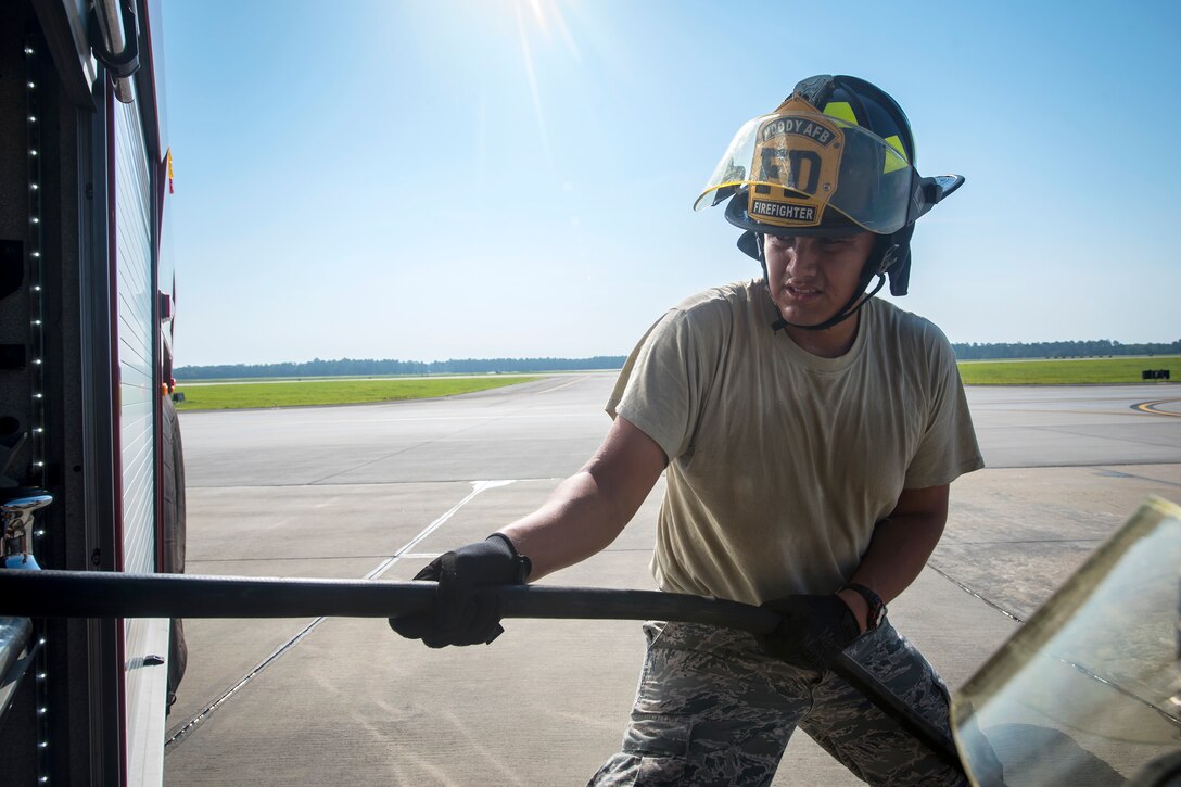 Airman 1st Class Carson Lafferty, 23d Civil Engineer Squadron (CES) firefighter, pulls a hose from a fire truck during an HH-60G Pave Hawk simulated rescue training scenario, June 20, 2018, at Moody Air Force Base, Ga. 23d CES firefighters conducted the training to evaluate their overall knowledge and preparation of how to properly shut down and rescue crew members from an HH-60. (U.S. Air Force photo by Airman 1st Class Eugene Oliver)