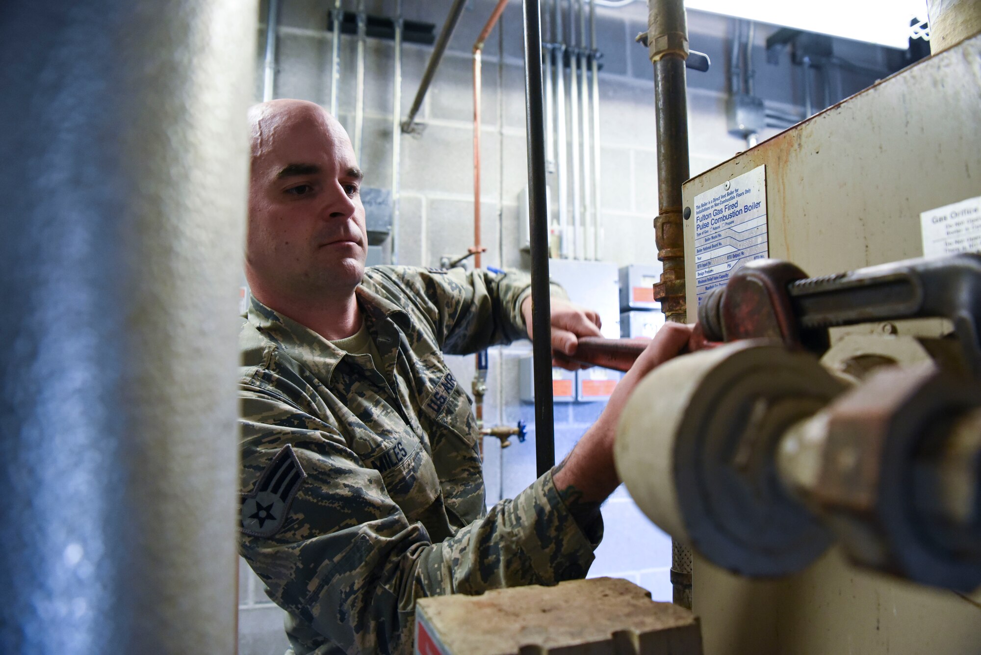 Senior Airman Tristan Miles, a 319th Civil Engineer Squadron heating, ventilation, air conditioning and refrigeration apprentice unscrews a water boiler June 20, 2018, on Grand Forks Air Force Base, North Dakota. Miles said that they open the front and back ends of the water boiler to check for any possible damage or overflow. (U.S. Air Force photo by Airman 1st Class Melody Wolff)