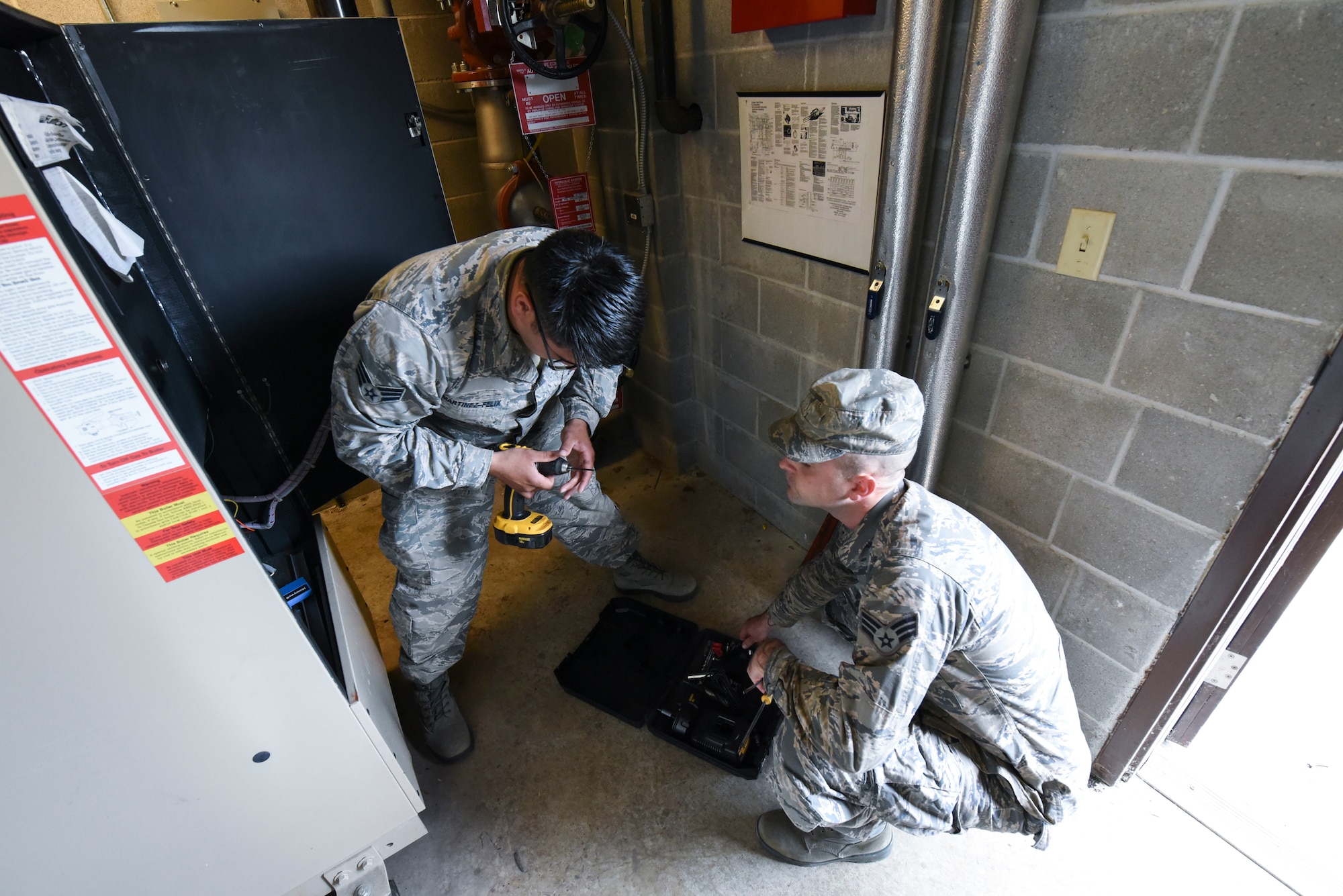 Senior Airman Kristian Martinez-felix, left, a 319th Civil Engineer Squadron heating, ventilation, air conditioning and refrigeration apprentice, and Senior Airman Tristan Miles, a 319th HVAC-R journeyman, maintain the water boilers June 20, 2018, on Grand Forks Air Force Base, North Dakota. Martinez-felix said that they typically work on the water boilers in the summertime to ensure they are prepared for the winter months. (U.S. Air Force photo by Airman 1st Class Melody Wolff)