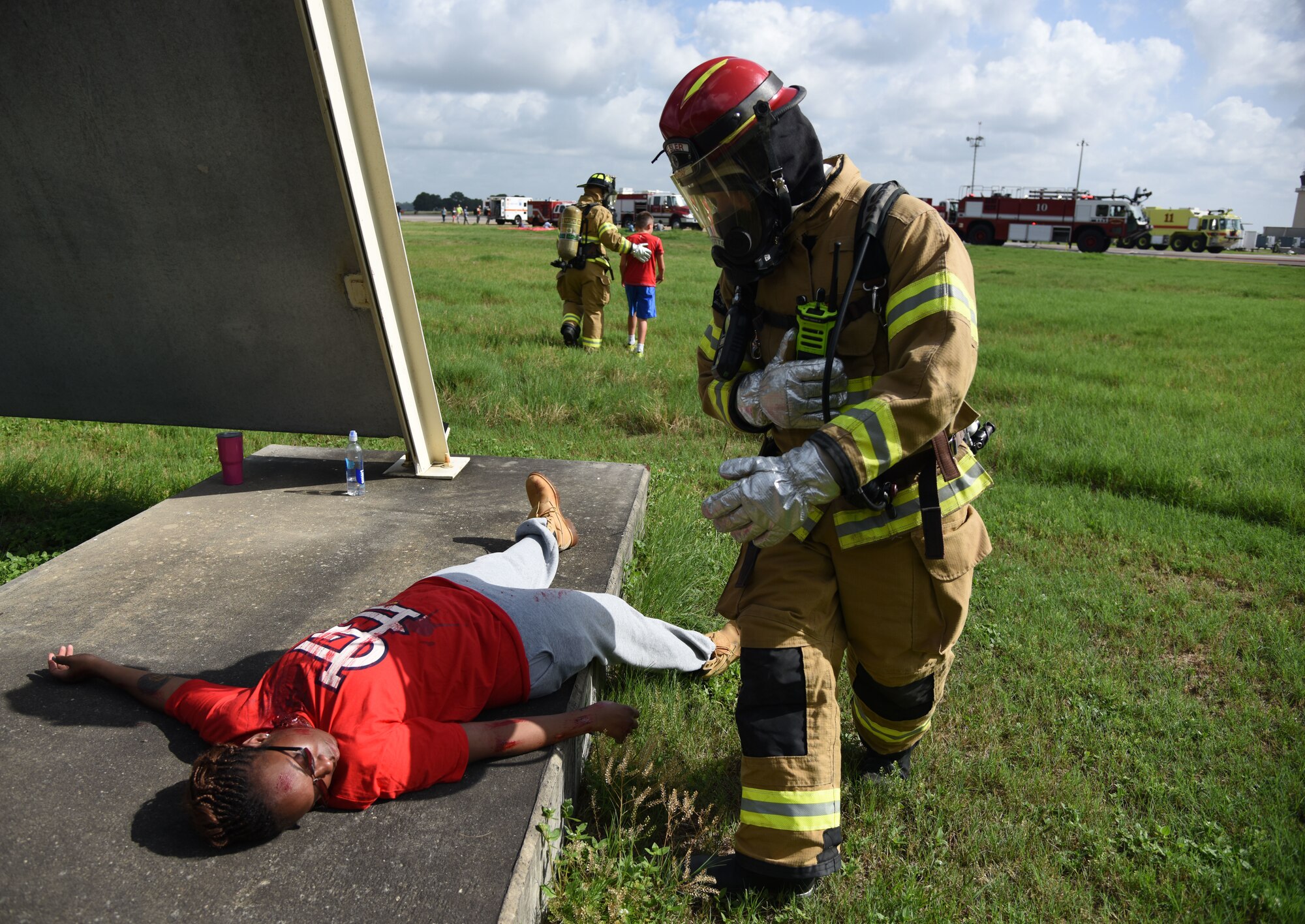 A Keesler Firefighter provides assistance to U.S. Air Force Tech. Sgt. Shanikqua Lucas, 81st Force Support Squadron manpower analyst, who portrays a “victim” during a major accident response exercise on the flight line at Keesler Air Force Base, Mississippi, June 21, 2018. The exercise scenario simulated a C-130J Super Hercules in-flight emergency causing a plane crash, which resulted in a mass casualty response event. This exercise tested the base’s ability to respond in a crisis situation. (U.S. Air Force photo by Kemberly Groue)