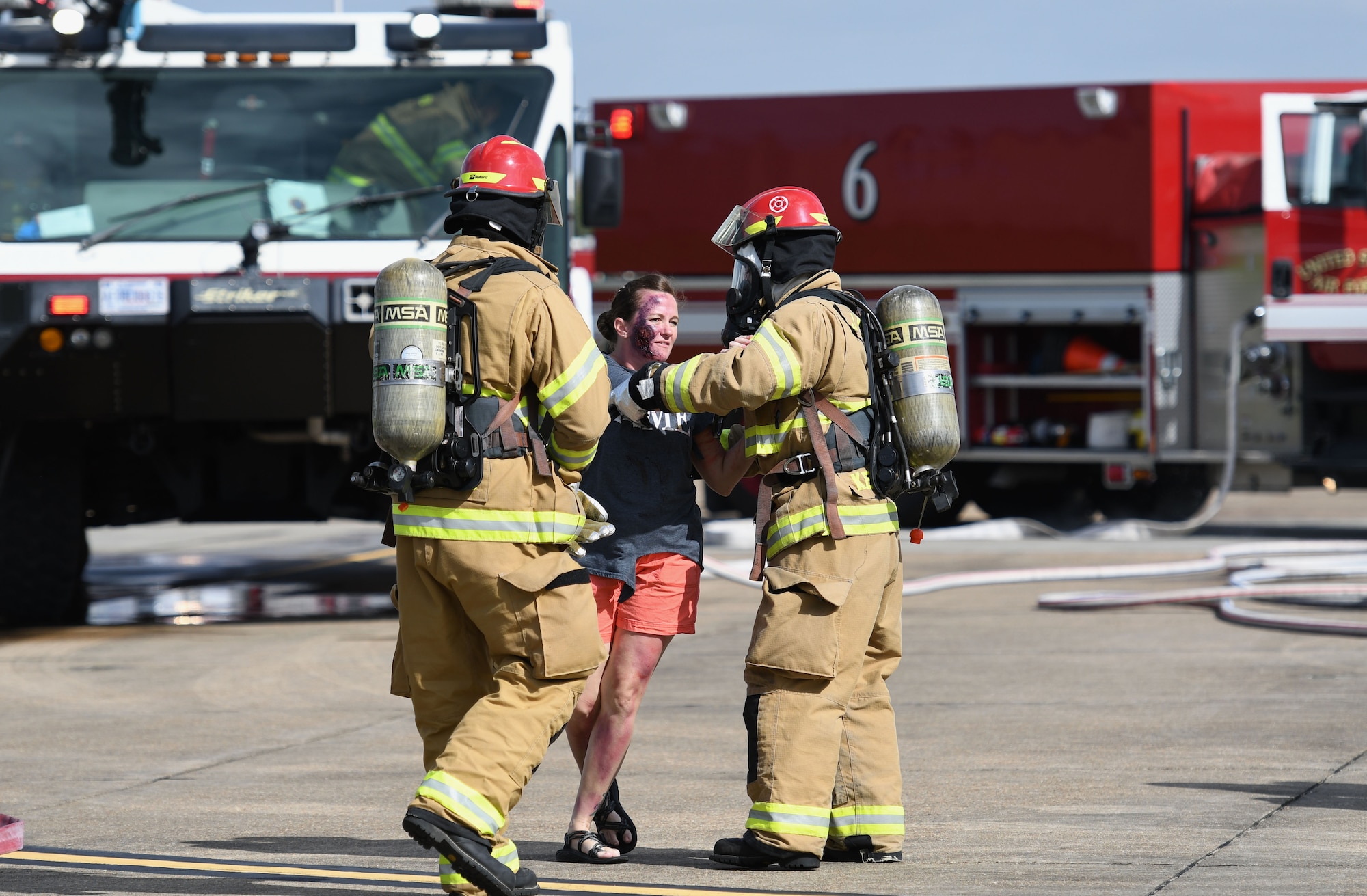 Keesler Firefighters provide assistance to U.S. Air Force Master Sgt. Tiffany Satterwhite, 81st Training Wing inspector general superintendent, who portrays a “victim” during a major accident response exercise on the flight line at Keesler Air Force Base, Mississippi, June 21, 2018. The exercise scenario simulated a C-130J Super Hercules in-flight emergency causing a plane crash, which resulted in a mass casualty response event. This exercise tested the base’s ability to respond in a crisis situation. (U.S. Air Force photo by Kemberly Groue)