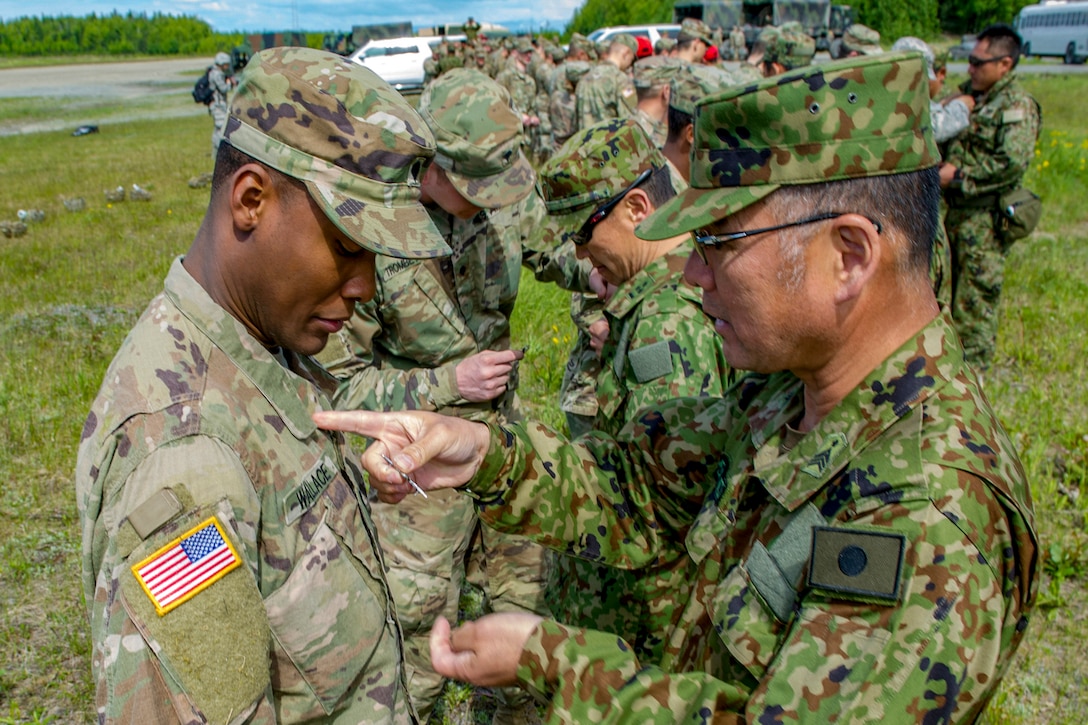 Japanese and U.S. troops stand in rows facing one another and exchange jump wings.