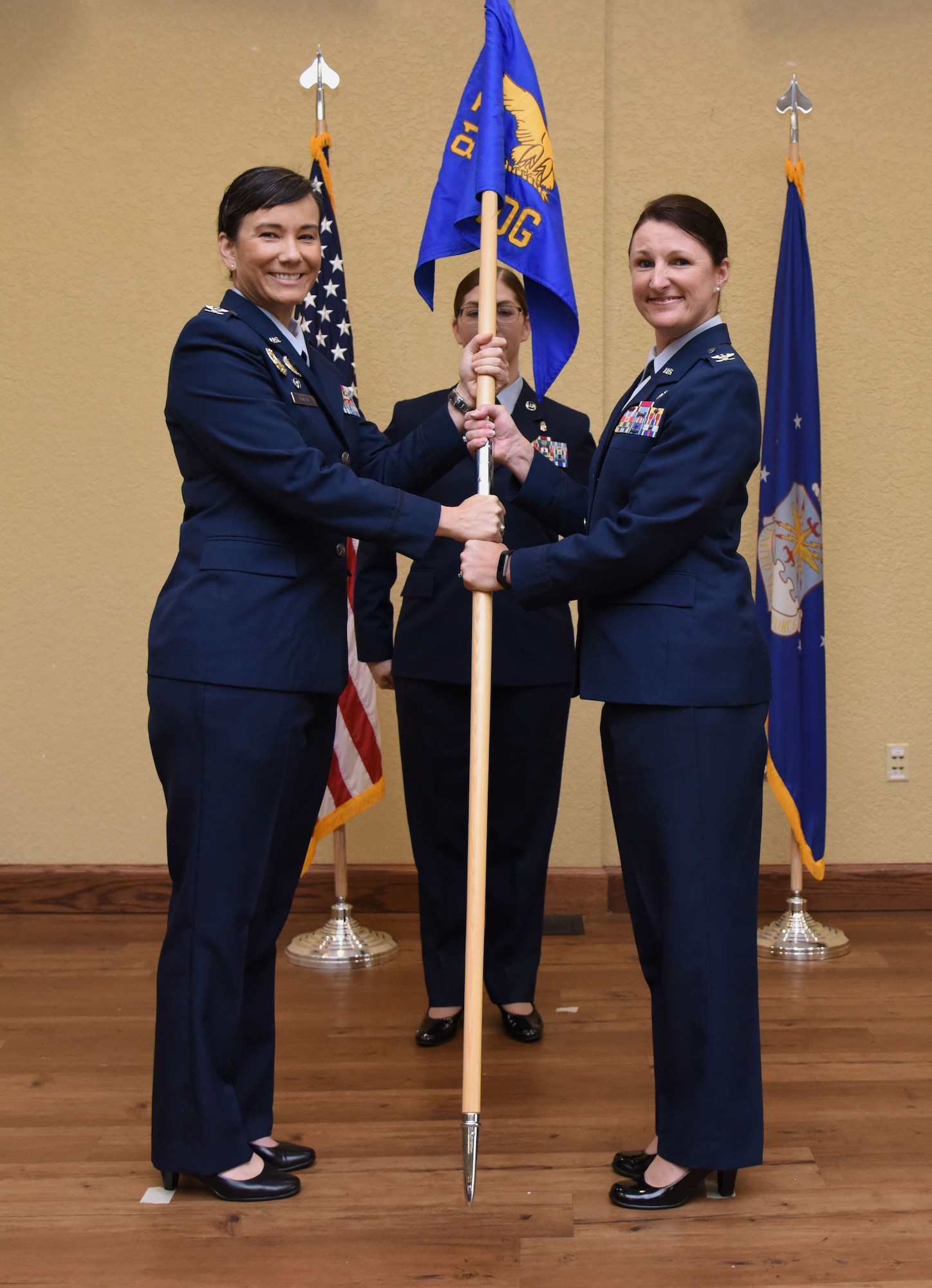 U.S. Air Force Col. Debra Lovette, 81st Training Wing commander, passes the 81st Medical Group guidon to Col. Beatrice Dolihite, incoming 81st MDG commander, during the 81st MDG change of command ceremony in the Bay Breeze Event Center at Keesler Air Force Base, Mississippi, June 22, 2018. The passing of the guidon is a ceremonial symbol of exchanging command from one commander to another. (U.S. Air Force photo by Kemberly Groue)