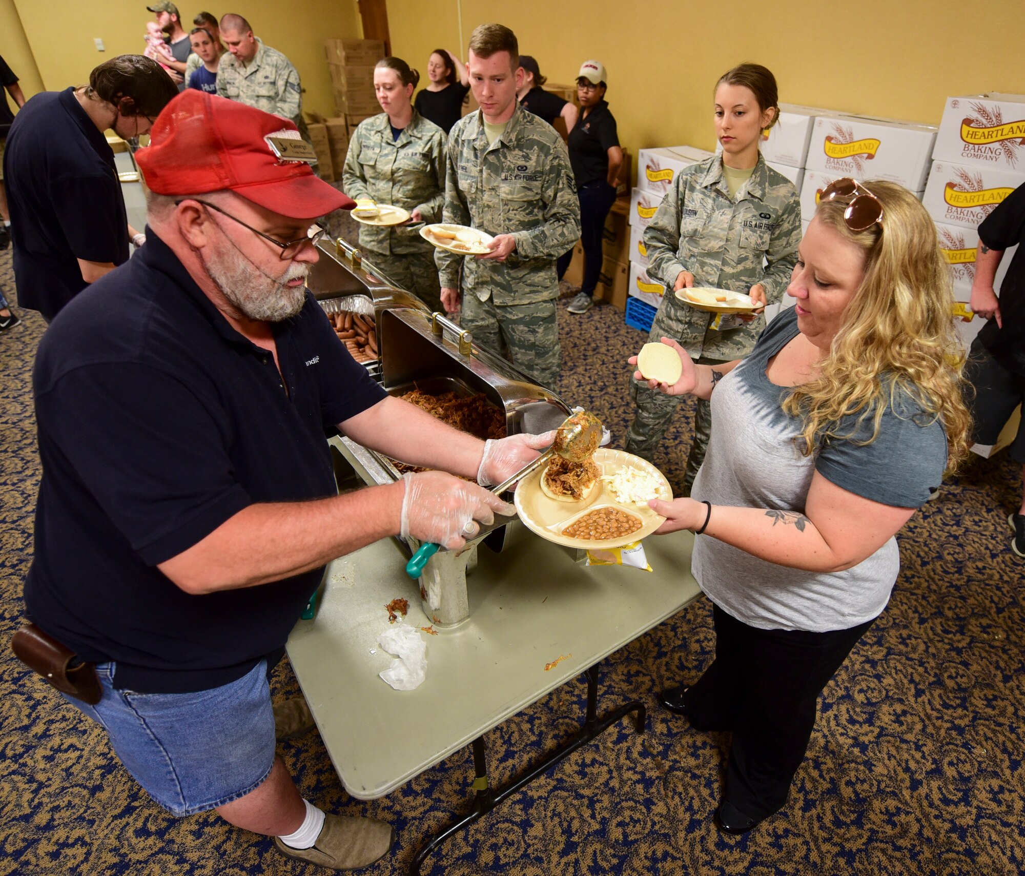 Airmen and their families go through a line to get a free barbeque lunch during the annual base picnic inside the Dakota’s Club on Ellsworth Air Force Base, S.D., June 22, 2018. The lunch was sponsored by local businesses and organizations. (U.S. Air Force photo by Senior Airman Randahl J. Jenson)