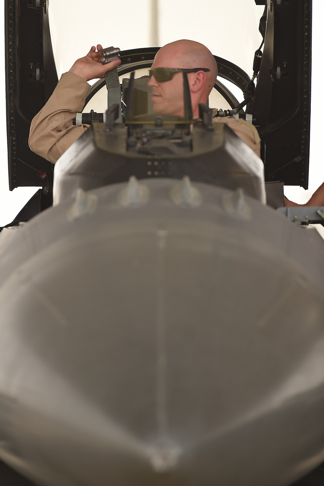 A pilot sits in the seat of a fighter aircraft