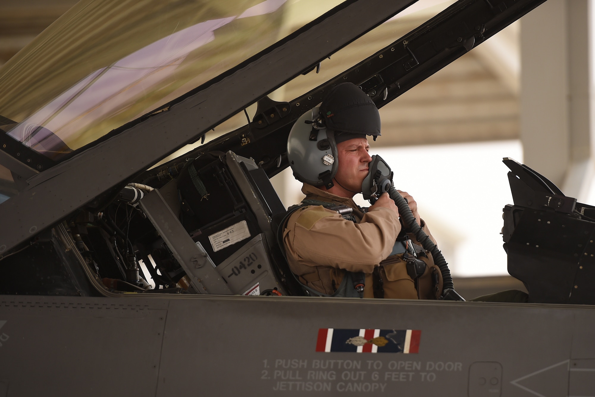 A pilot sits in the seat of a fighter jet