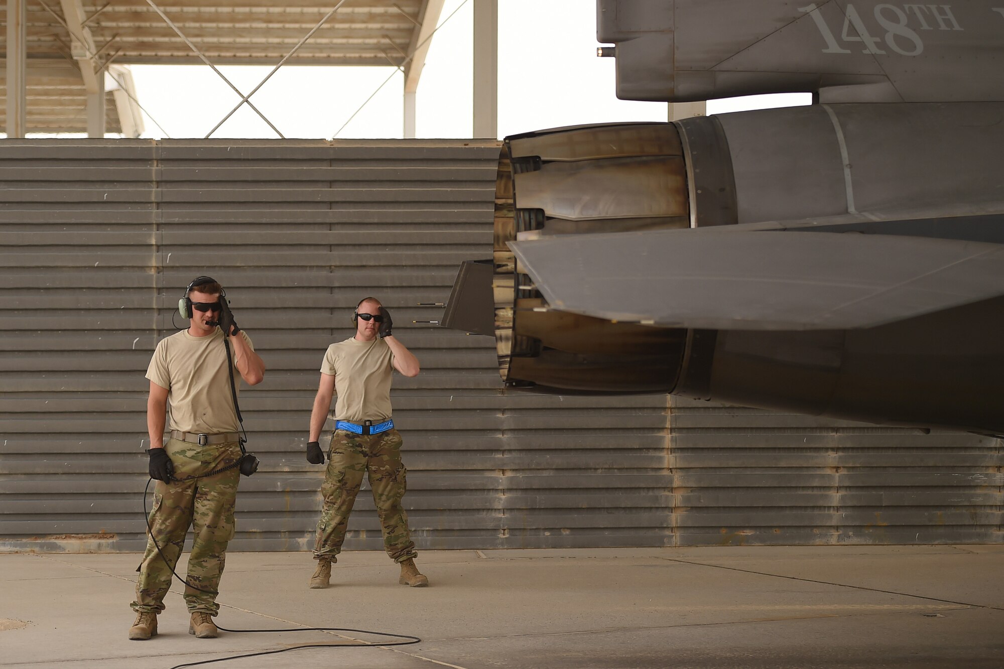 Two Airmen stand behind an F-16
