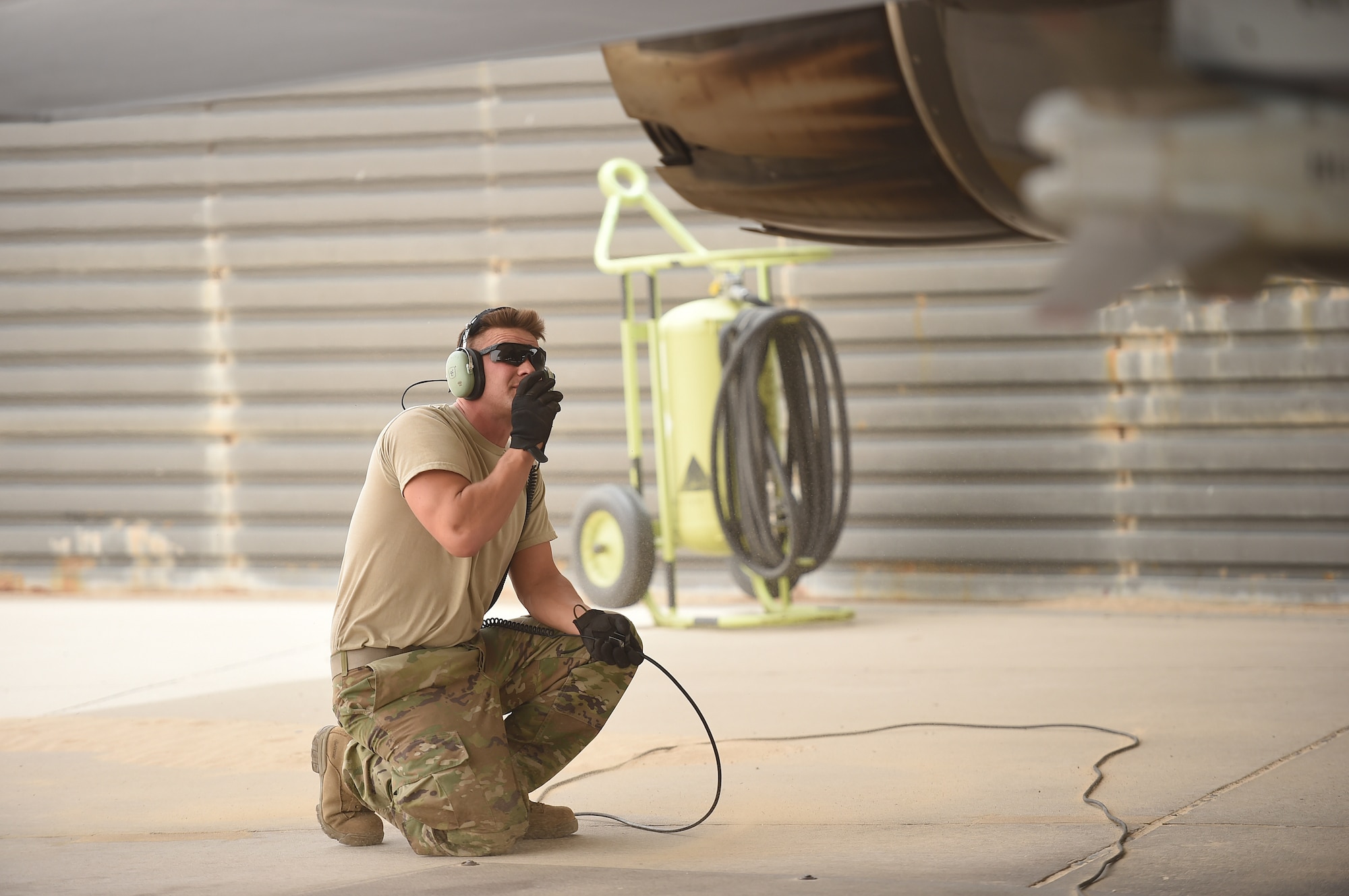 Airman takes a knee behind F-16.