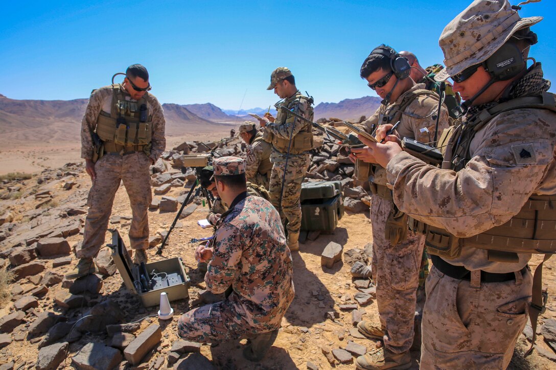 Service members set up and test communication and other equipment in a desert environment.