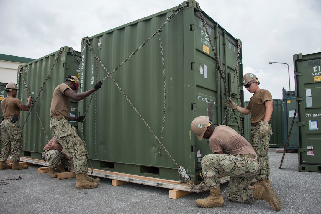 Seabees assigned to Naval Mobile Construction Battalion (NMCB) 5, chain a container to a pallet during a 48-hour Mount-Out Exercise (MOX) in Okinawa, Japan June 19. The MOX simulates one of the core capabilities of a construction battalion to deploy an air detachment, along with construction equipment, within 48-hours to any required location around the globe. NMCB 5 is forward deployed to execute construction, humanitarian and foreign assistance, and theater security cooperation support of United States Pacific Command.