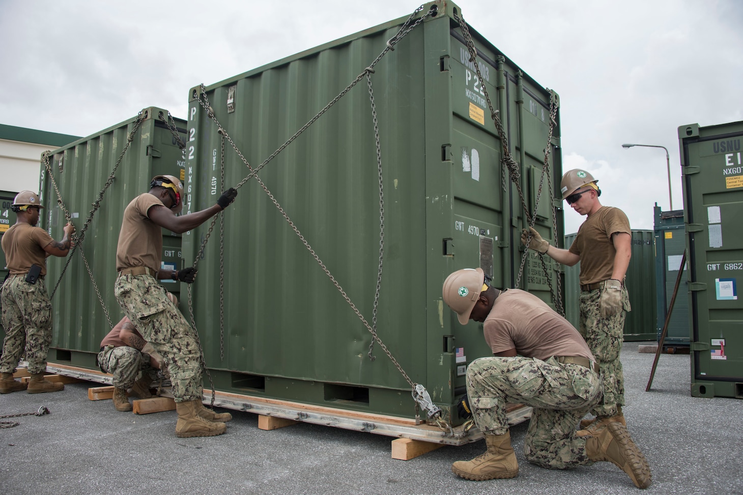 Seabees assigned to Naval Mobile Construction Battalion (NMCB) 5, chain a container to a pallet during a 48-hour Mount-Out Exercise (MOX) in Okinawa, Japan June 19. The MOX simulates one of the core capabilities of a construction battalion to deploy an air detachment, along with construction equipment, within 48-hours to any required location around the globe. NMCB 5 is forward deployed to execute construction, humanitarian and foreign assistance, and theater security cooperation support of United States Pacific Command.