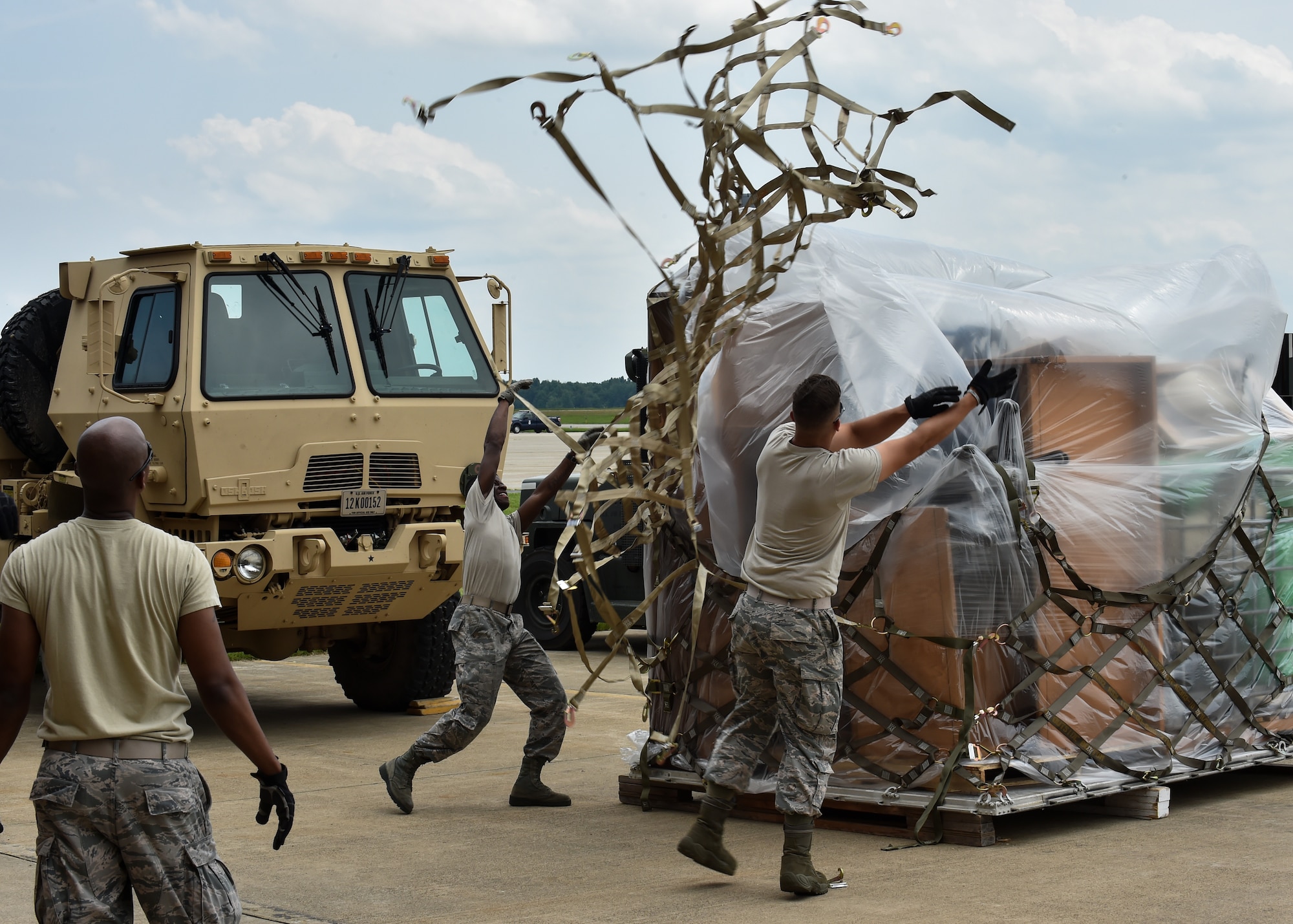 Staff Sgt. Donald Irby watches as Airman 1st Class Kevin Mills and Staff Sgt. Justin Knight, all 76th Aerial Port Squadron (APS) aerial transporters, toss a cargo net over a pallet of supplies on the Youngstown Air Reserve Station flightline, June 3.