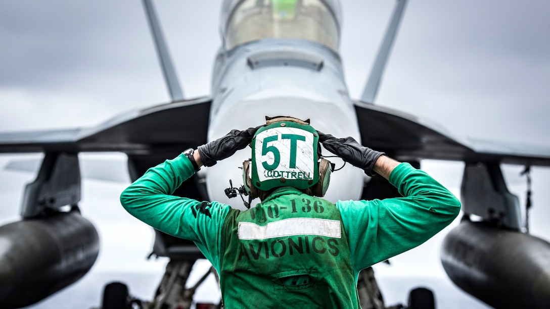 A sailor uses a hand signal.