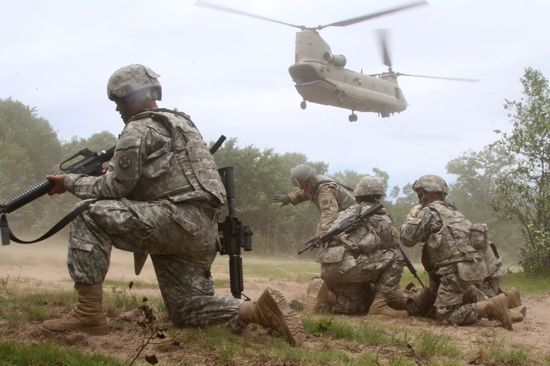 Soldiers prepare for a helicopter to land nearby.