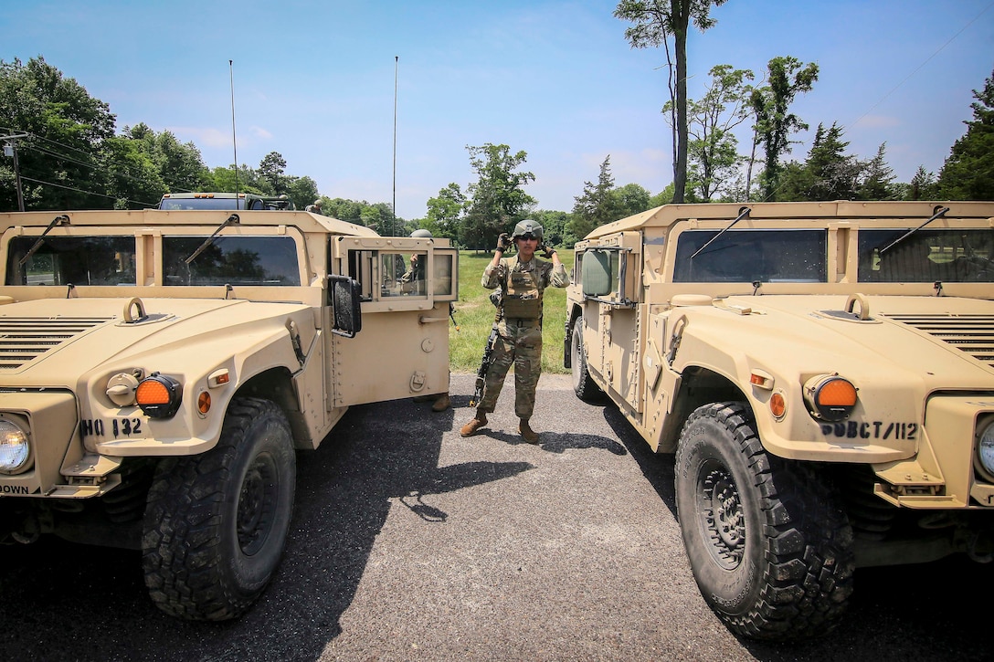 A soldier ground-guides Humvees.