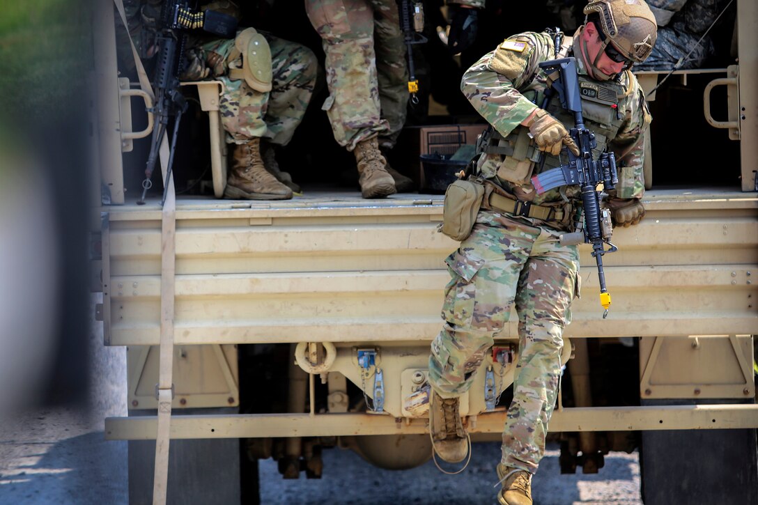 Soldiers jump from the back of a tactical vehicle.