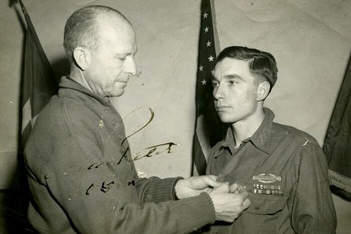 In a historic photo, a person pins a medal on a soldier.