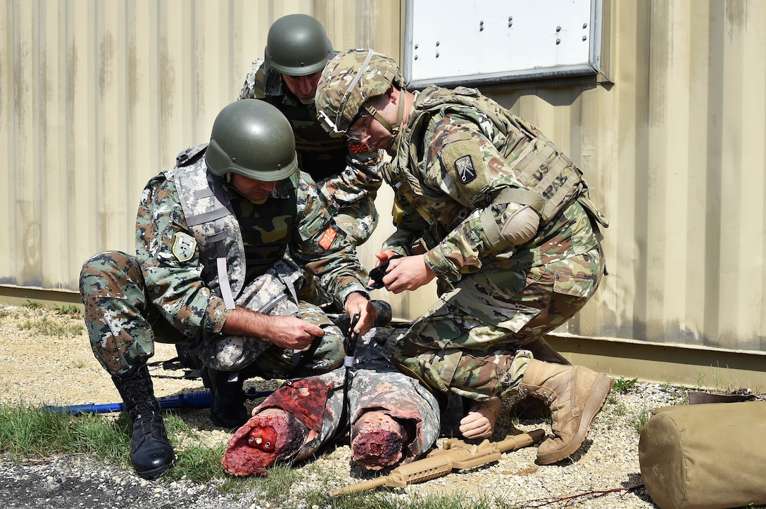 A U.S. soldier, right, and Macedonian soldiers apply first aid to a simulated casualty.