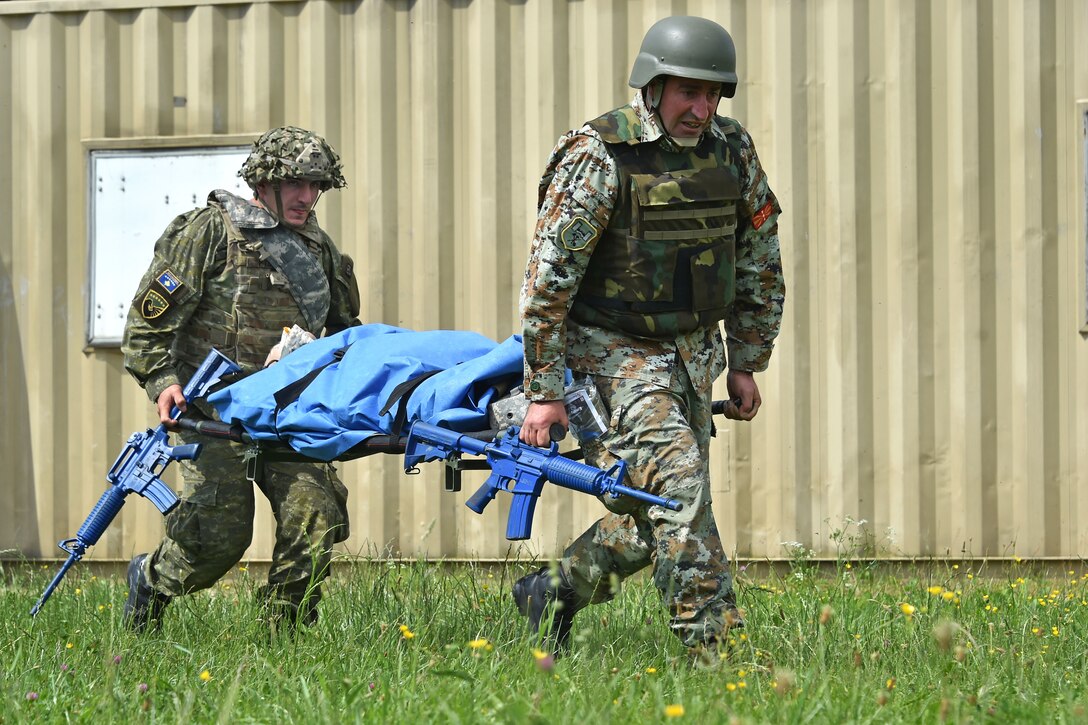 A Kosovar and a Macedonian soldier transport a simulated casualty on a stretcher.