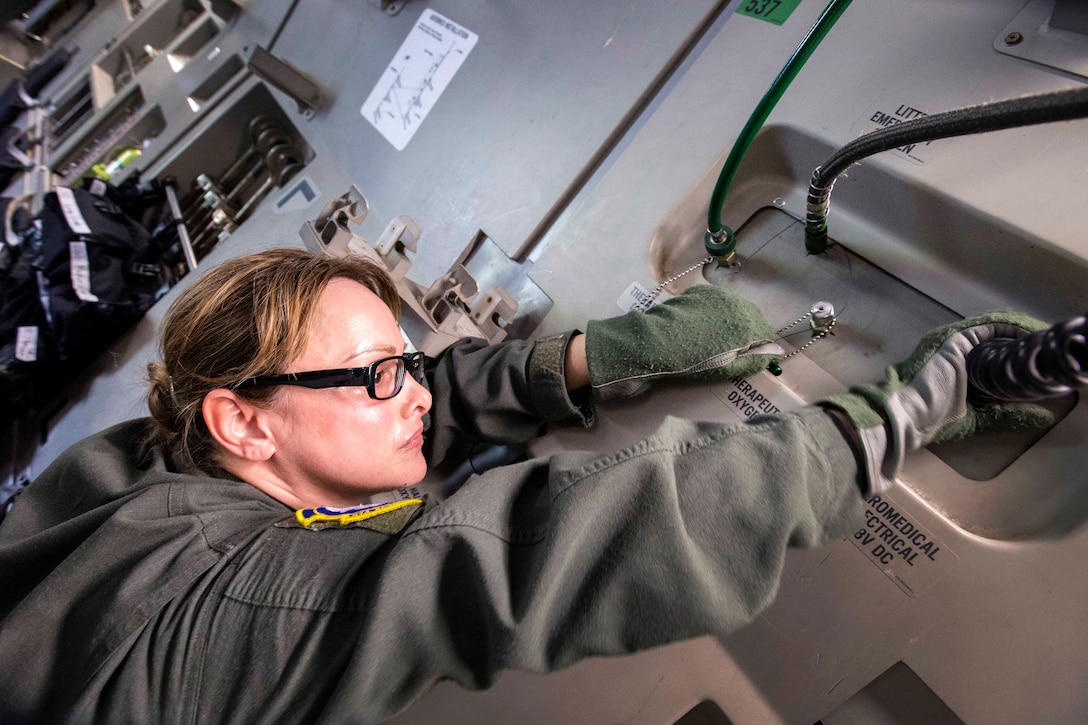 An airman powers a litter stanchion onboard a C-17 Globemaster III.