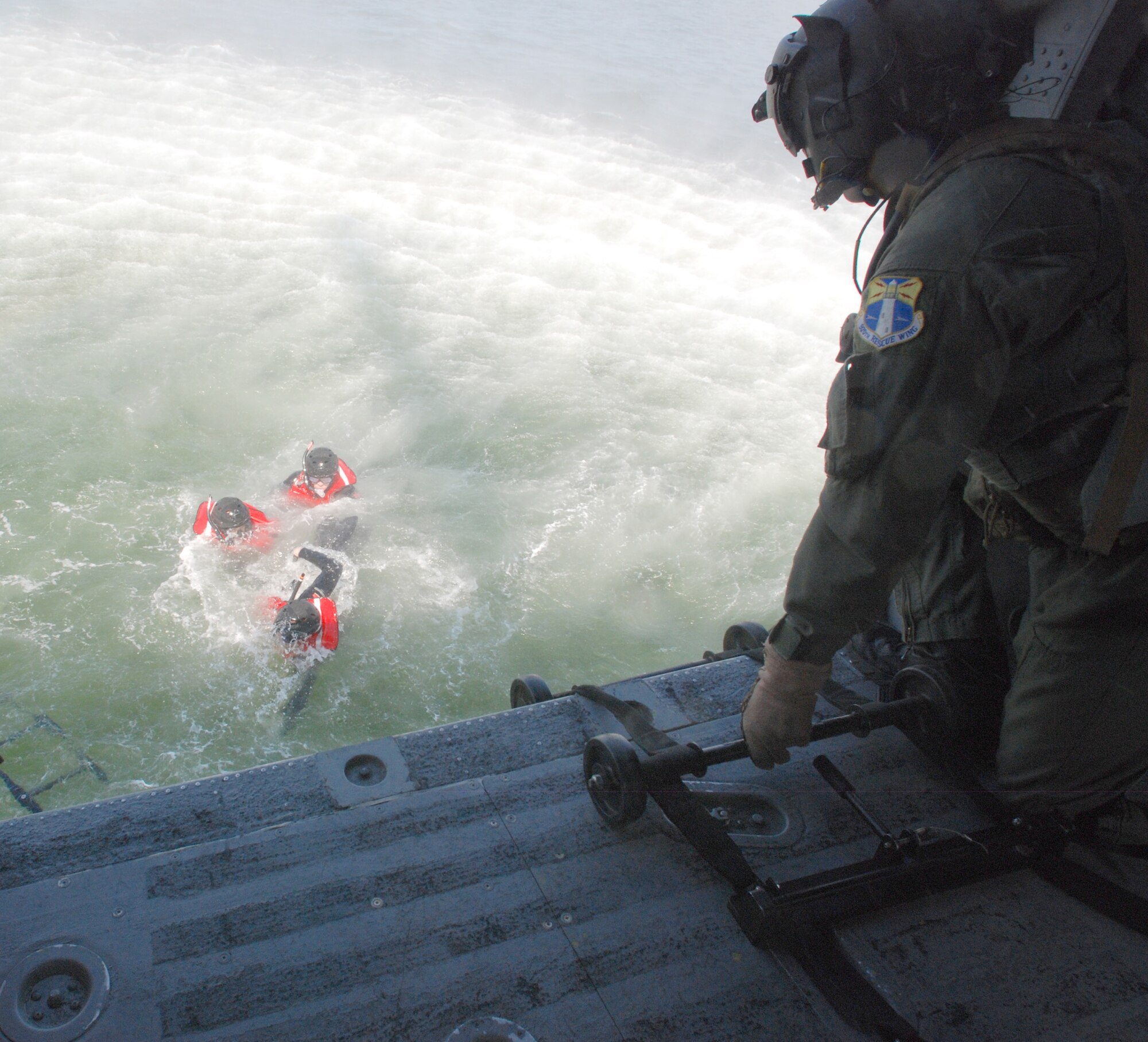 During a training mission, Air Force Reserve Master Sgt. Peter Pavenski, HH-60G Pave Hawk helicopter aerial gunner, 920th Rescue Wing here, assists pararescuemen with boarding the helicopter by lowering a rope ladder and guiding them while they climb from the Banana River next to Patrick Air Force Base. (U.S. Air Force photo/Staff Sgt. Leslie Kraushaar)