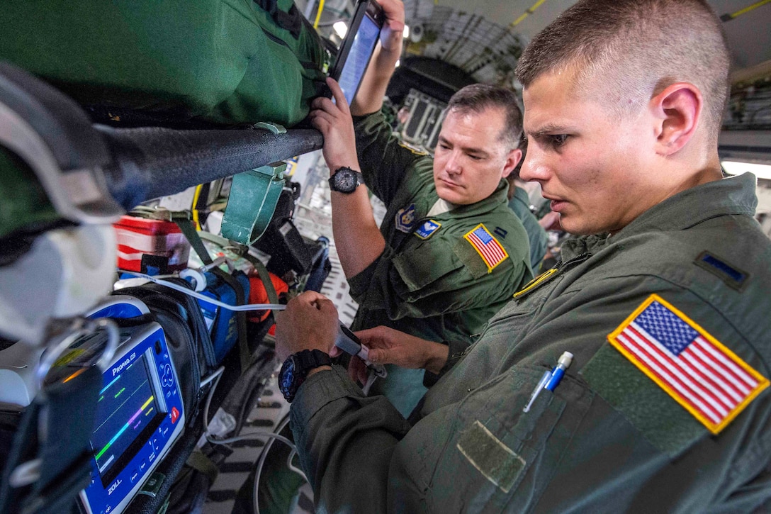 Flight nurses perform a systems check on a vital signs monitor/defibrillator onboard a C-17 Globemaster III.