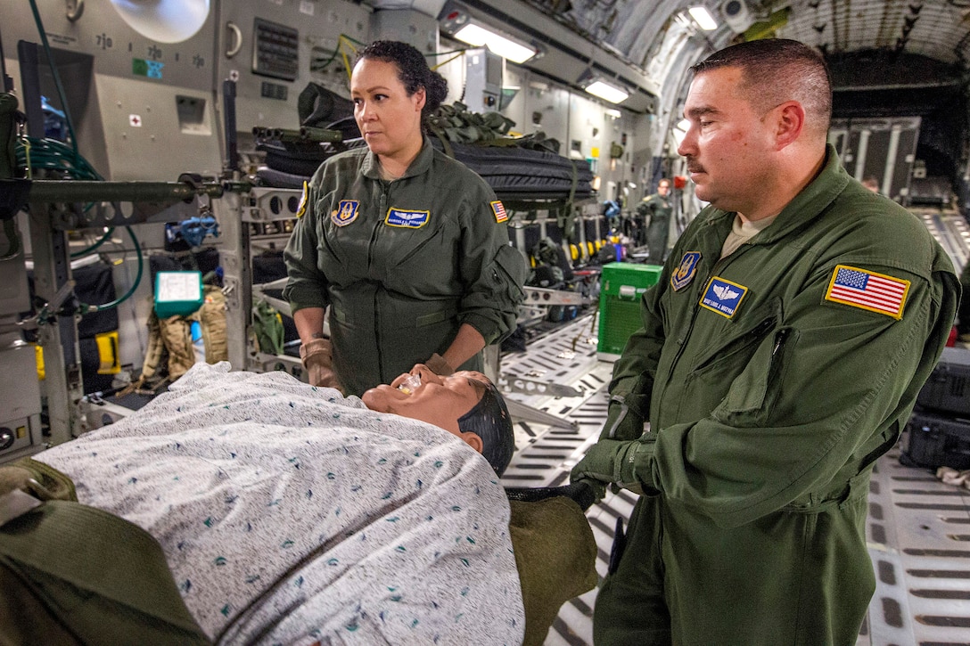 Aeromedical evacuation technicians prepare to load a litter onto a litter stanchion onboard a C-17 Globemaster III.