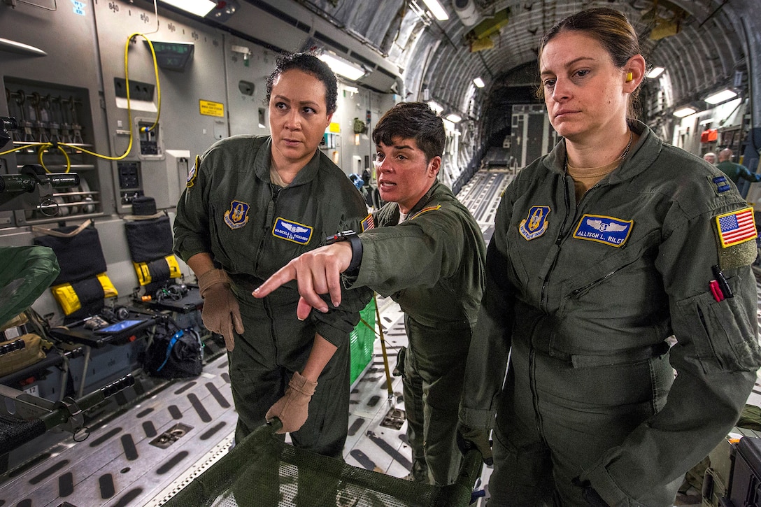 A senior flight examiner directs team members where to place a litter onboard a C-17 Globemaster III.