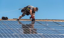 Wyatt Whelan, PosiGen install supervisor, secures a photovoltaic panel to a roof May 11, 2018, at Dover Air Force Base, Del. One hundred forty-nine houses in the Dover Family Housing community are scheduled to have the panels installed on them. (U.S. Air Force photo by Roland Balik)