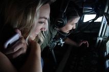 A 77th Fighter Squadron F-16CM Fighting Falcon pilot’s wife, left, smiles as she watches a 72nd Air Refueling Squadron KC-135R Stratotanker in-flight refueling technician, right, refuel her husband’s jet during an incentive flight over the Atlantic Ocean, June 20, 2018.