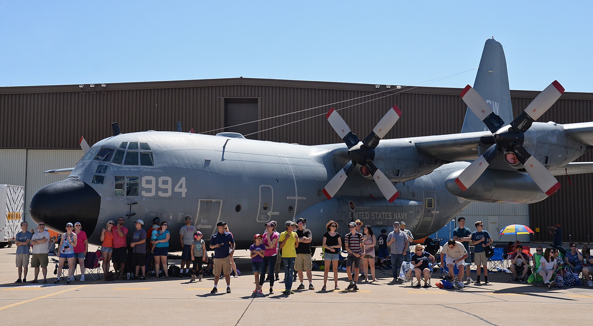 Airshow visitors use the large shadow cast by a U. S. Navy C-130H Hercules to keep cool during the Warriors over the Wasatch Air and Space Show June 23, 2018, at Hill Air Force Base, Utah. (U.S. Air Force photo by Alex R. Lloyd)