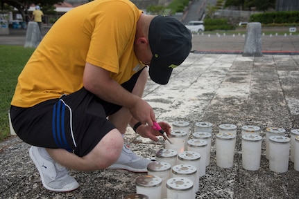 Aviation Electrician's Mate Chief Greg Brown, from Wilmington, N.C., assigned to Patrol Squadron (VP) 4, lights a candle at Okinawa Peace Memorial Park during the Lamplight of Peace event. More than 30 U.S. Navy volunteers carefully placed thousands of ceremonial candles at the park in Itoman City, June 22, to honor the more than 250,000 Japanese and American lives lost during the Battle of Okinawa, the third deadliest battle ever fought by U.S. service members.