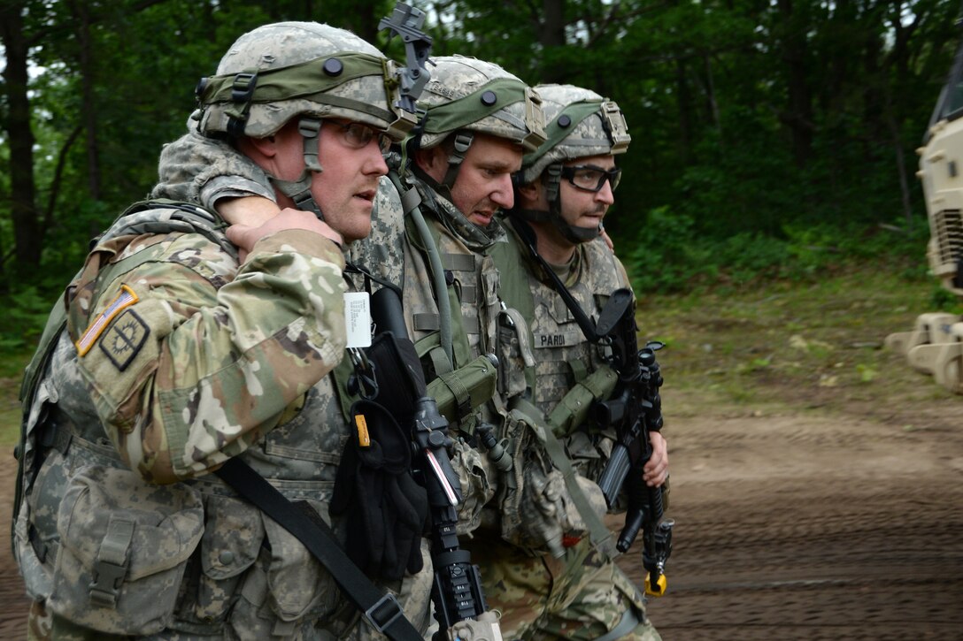 Soldiers assist a role-playing casualty to a medical ambulatory Humvee.