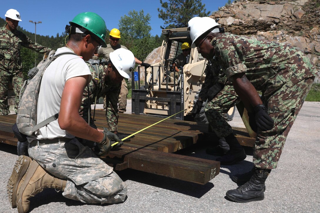 A U.S. soldier and Suriname soldier take measurements during a bridge repair project.