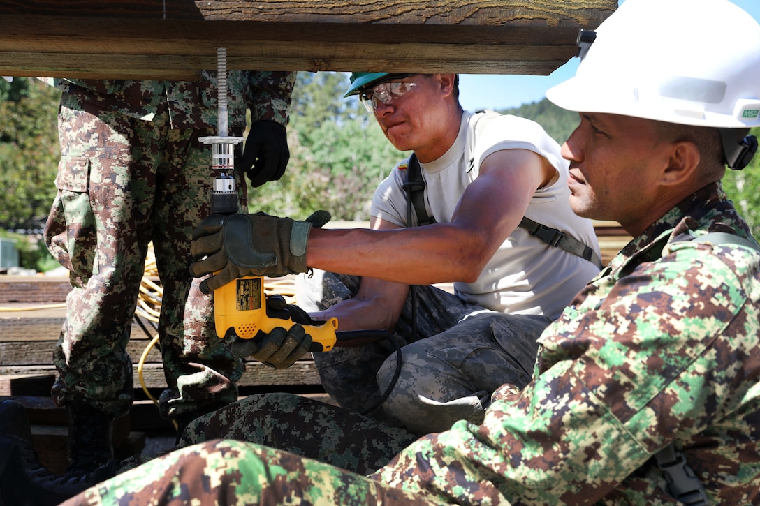 A U.S. and Suriname soldier secure a joist during a bridge repair project.