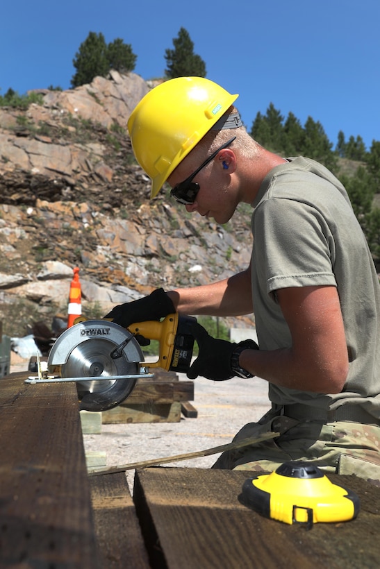A soldier saws wood planks to be used during a bridge repair project.