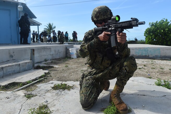 A Mexican Marine takes a knee while aiming a rifle.