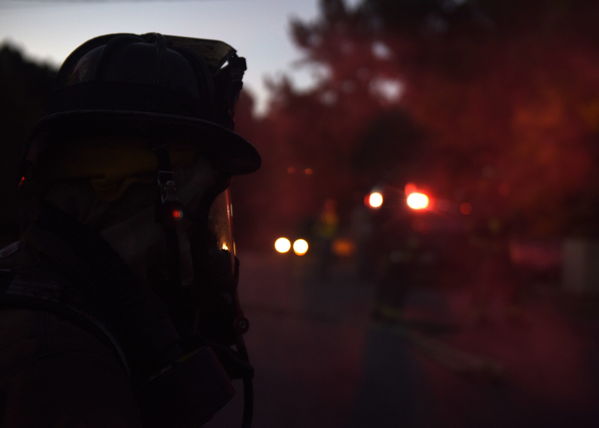 People in uniforms participate in an exercise wearing various equipment and gas masks.