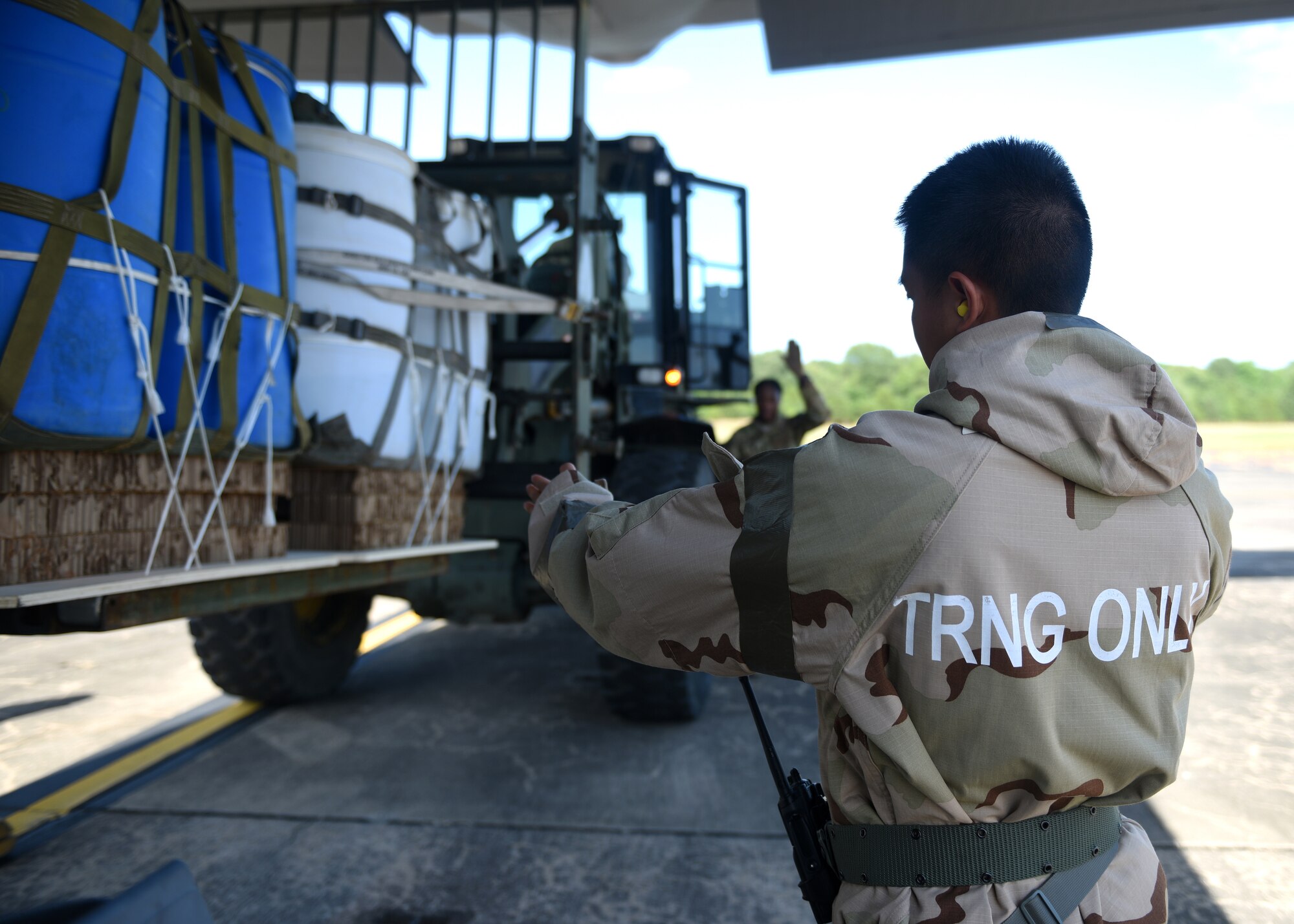 People in uniforms participate in an exercise wearing various equipment and gas masks.