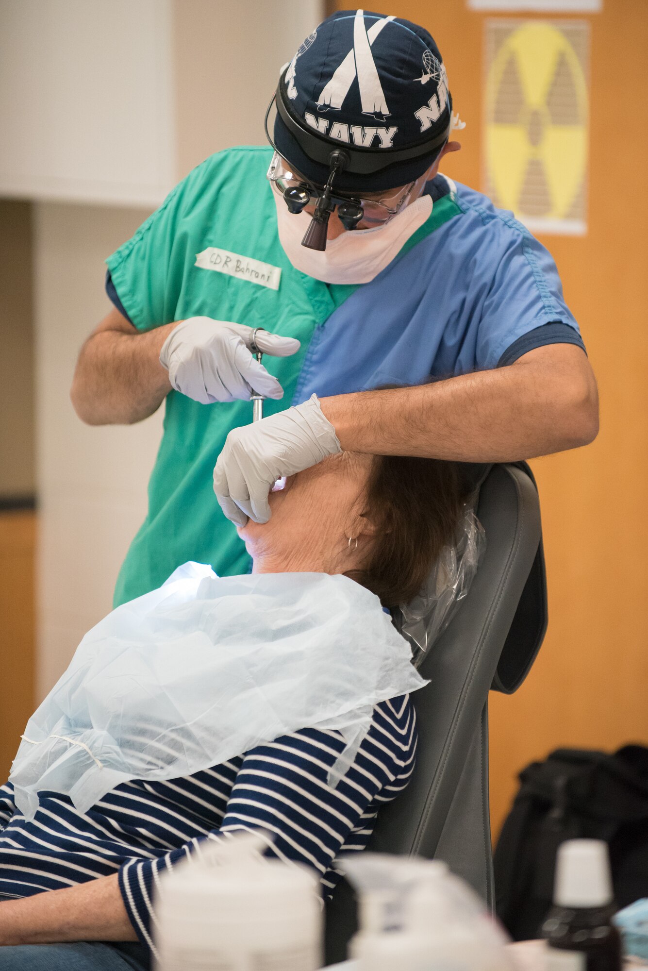 U.S. Navy Cmdr. Hayder Bahrani, a dentist from Expeditionary Medical Facility Great Lakes in Illinois, prepares a patient for a tooth extraction at a health-care clinic being operated by the Air Guard and U.S. Navy Reserve at Breathitt County High School in Jackson, Ky., June 20, 2018. The Jackson clinic is one of four that comprised Operation Bobcat, a 10-day mission to provide military medical troops with crucial training in field operations and logistics while offering no-cost health care to the residents of Eastern Kentucky. The clinics, which operated from June 15-24, offered non-emergent medical care; sports physicals; dental cleanings, fillings and extractions; eye exams and no-cost prescription eye glasses. (U.S. Air National Guard photo by Lt. Col. Dale Greer)