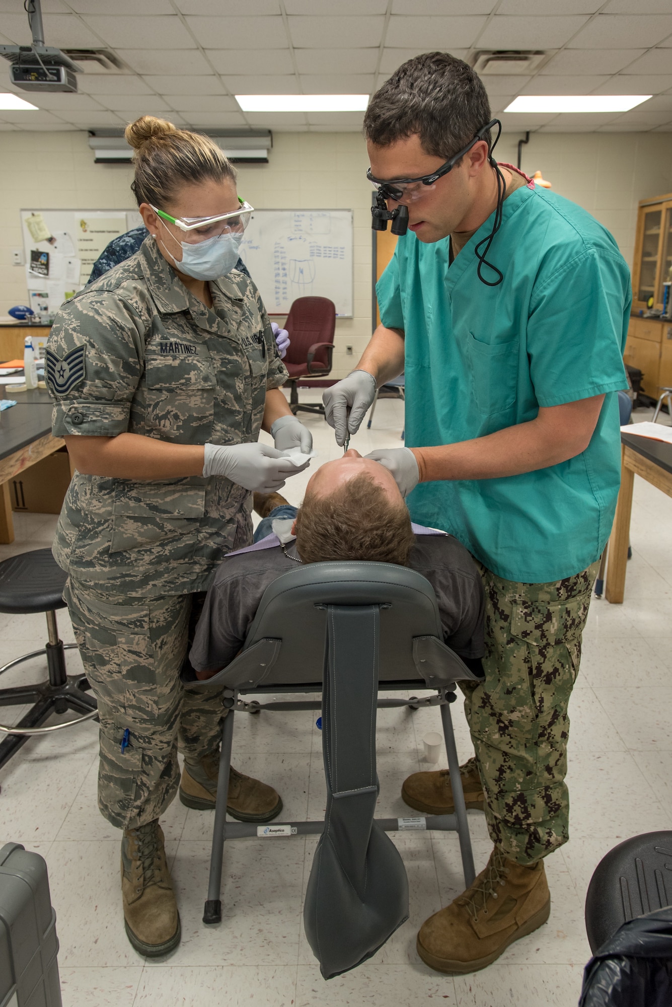 U.S. Air Force Tech. Sgt. Jessica Martinez (left), a dental technician from the Iowa Air National Guard’s 185th Refueling Wing, and U.S. Navy Lt. Cmdr. Jay Ross, a dentist from Expeditionary Medical Facility Camp Pendleton in California, perform a dental procedure at a health-care clinic at Owsley County High School in Booneville, Ky., June 24, 2018. The clinic is one of four that comprised Operation Bobcat, a 10-day mission to provide military medical troops with crucial training in field operations and logistics while offering no-cost health care to the residents of Eastern Kentucky. The clinics, which operated from June 15-24, offered non-emergent medical care; sports physicals; dental cleanings, fillings and extractions; eye exams and no-cost prescription eye glasses. (U.S. Air National Guard photo by Lt. Col. Dale Greer)