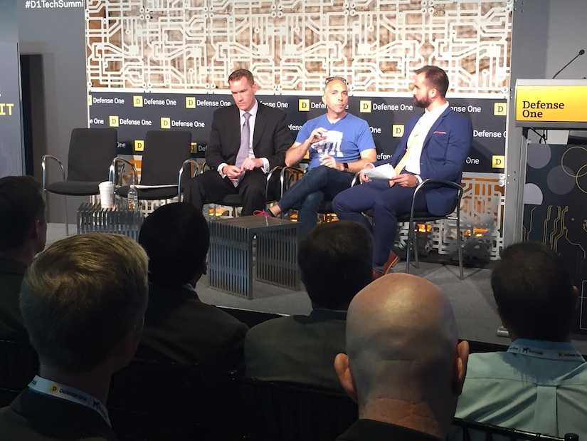 Three men speak as a panel at a technology summit.